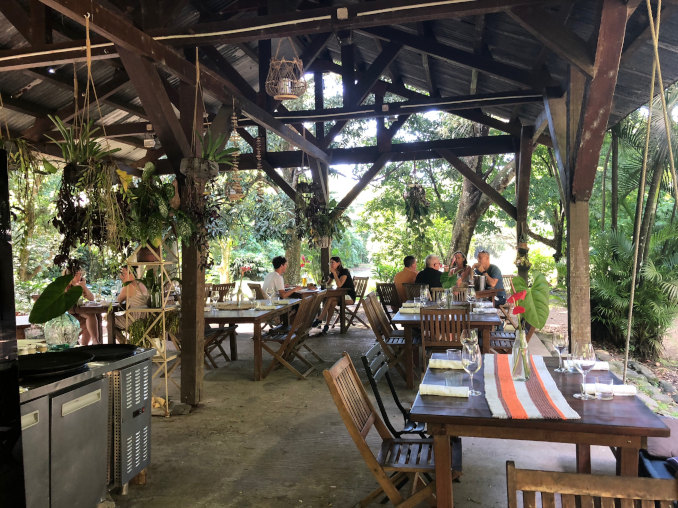 Holztische und Stühle unter einem Holzdach, das Restaurant im Regenwald der Habitation Céron, Martinique