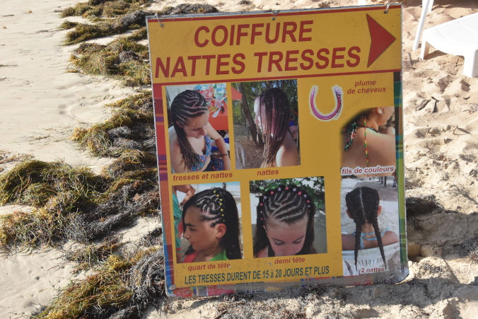 schild am strand martinique werbeschild fuer tresses afrikanische zoepfe flechten